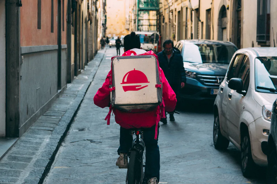 A delivery rider cycling down a narrow street