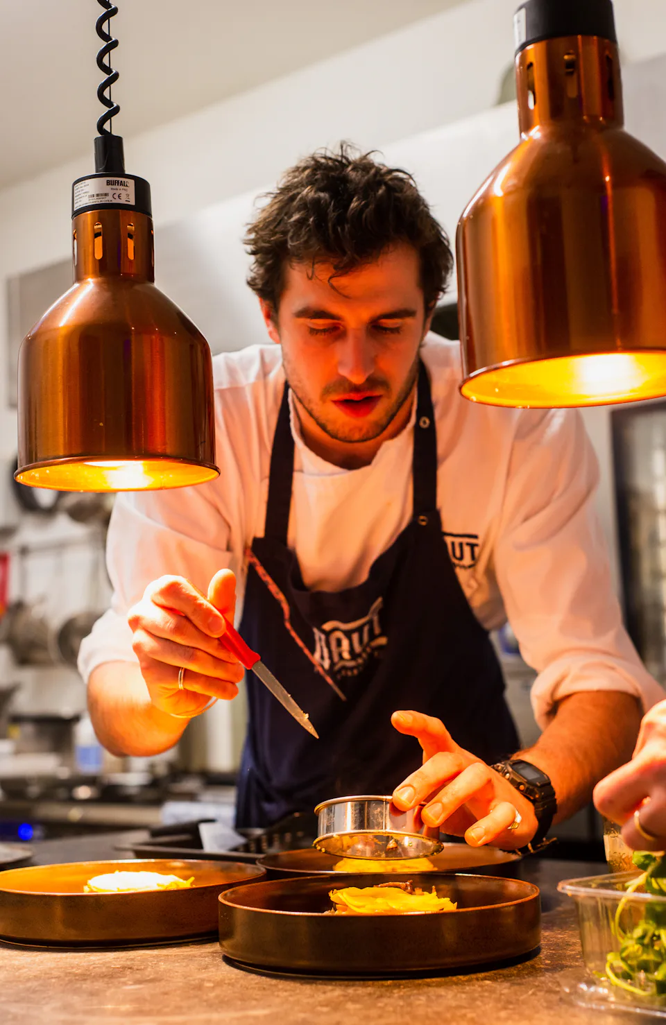 A chef plating under heat lamps